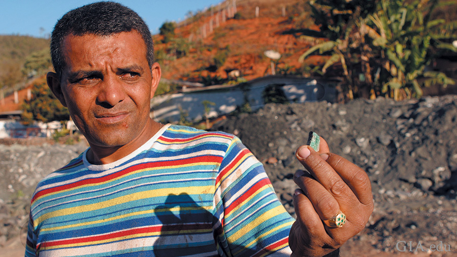 Miner holding a rough emerald at the Capoeirana mining area where the May birthstone is found.