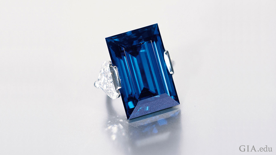 The famed Rockefeller Sapphire weighs 62.02 carats and is flanked by two cut-cornered triangular cut diamonds, mounted in a platinum ring to show off the blue September birthstone.