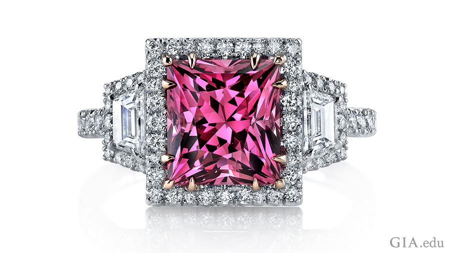 The August birthstone is featured in a 3.55 carat princess cut pink spinel ring surrounded by round brilliant diamonds and two trapezoid diamonds.