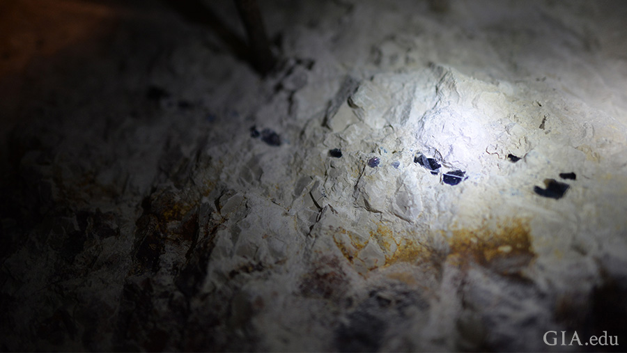 Light shines on the surface of the Lightning Ridge mine where the October birthstone is found, revealing black opal nodules in a line.