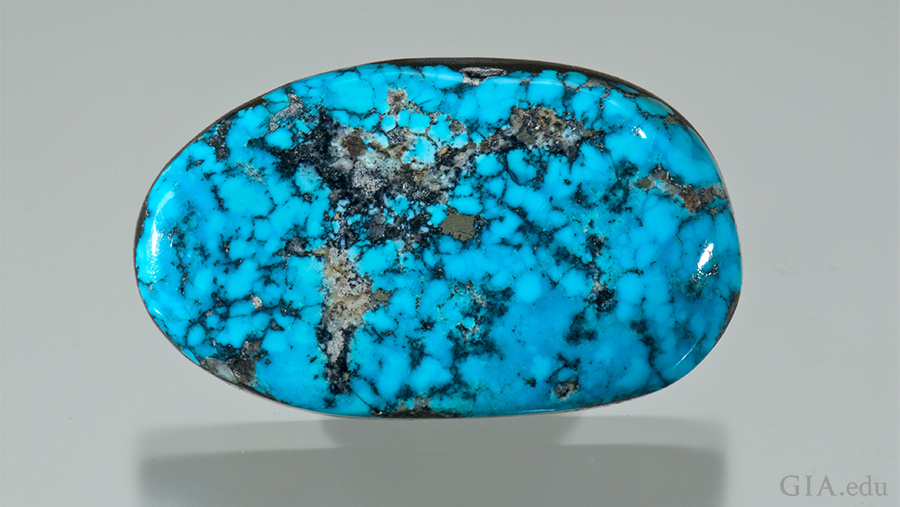 This 46.28 carat December birthstone is a medium green blue turquoise free-form cabochon with black specks.